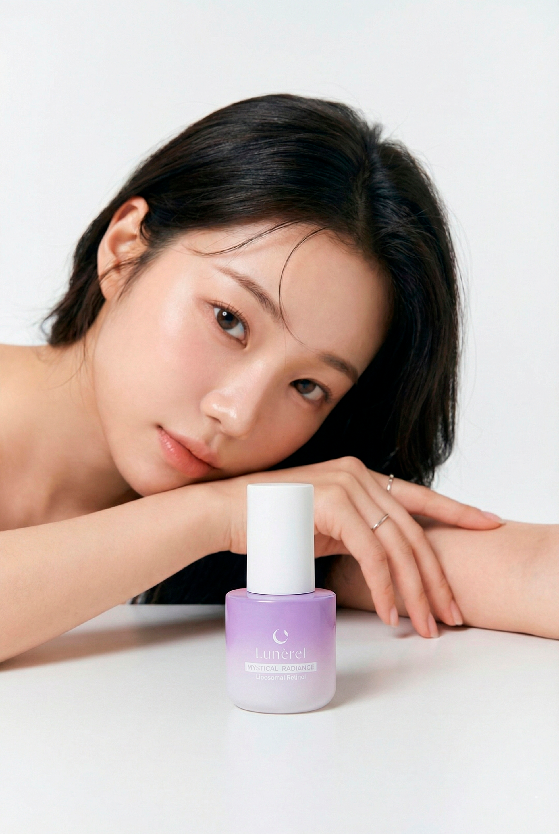 Model with Lunérel Mystical Radiance Serum bottle on light background