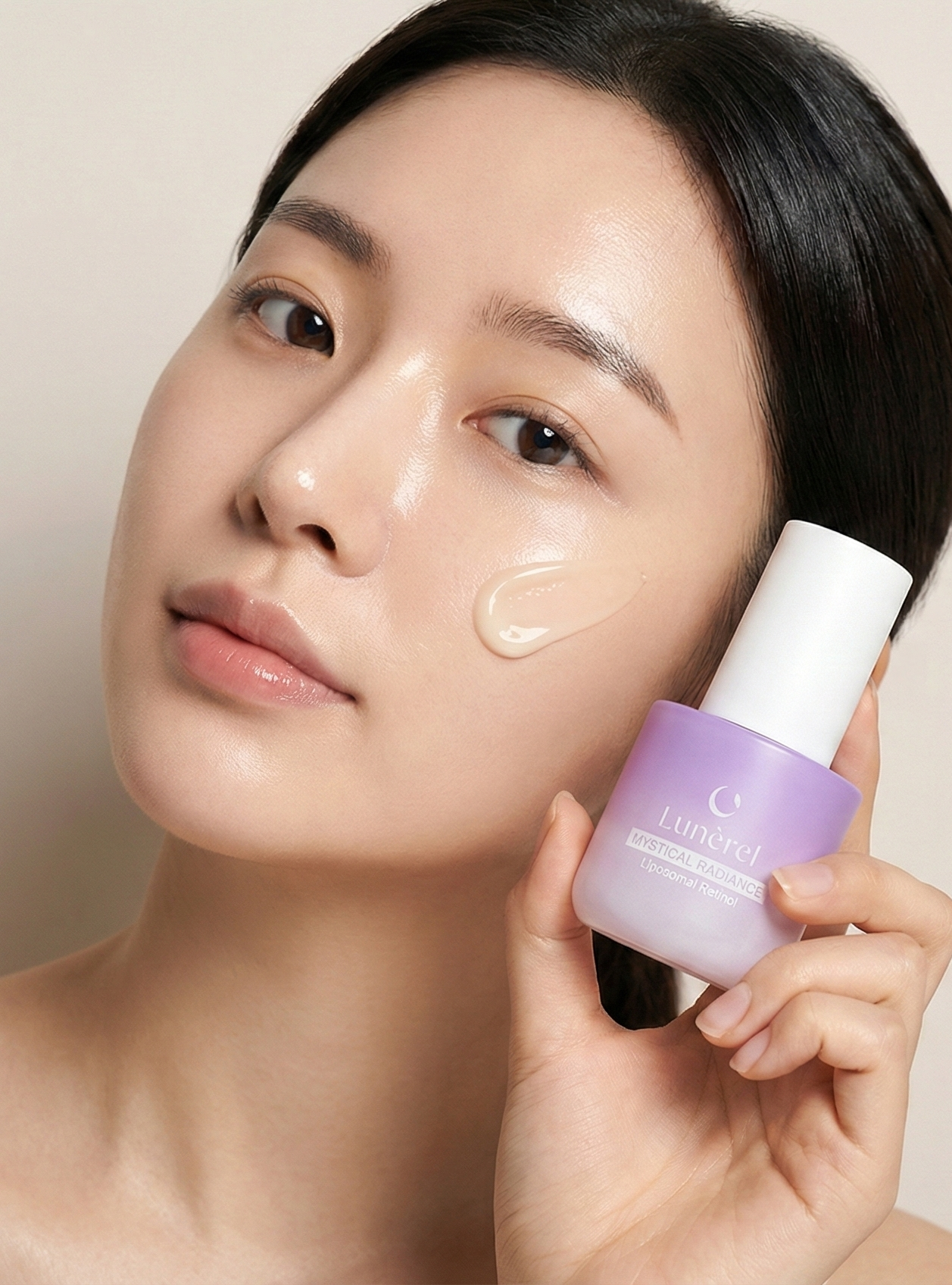 Woman holding a Lunérel Mystical Radiance Serum with visible cream on her face